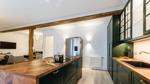 Une cuisine moderne avec des meubles de couleur sombre, un plan de travail en bois et un réfrigérateur encastré.