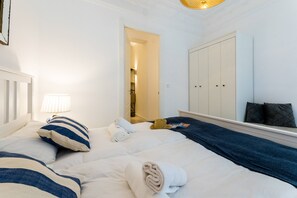A hotel room with two beds, a wardrobe, a lamp, and a door leading to a bathroom. - BALEA SUITE APARTMENT (San Sebastián)