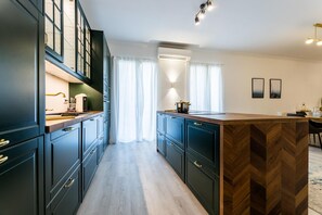 Een moderne keuken met donkere kastjes, een houten eiland en een ingebouwde oven.