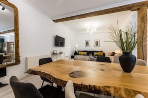 A modern dining area with a large wooden table, chairs, and a mirror.