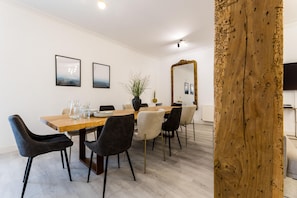 A dining area with a wooden table, black and white chairs, and a large mirror.
