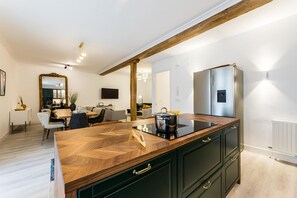 A modern kitchen with a wooden countertop, built-in cabinets, and a stainless steel refrigerator.