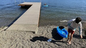 A wooden pier extending into a lake with a kayak and paddle on the shore. - Charming Lakefront Cabin on Mason Lake with Pebble Beach and Private Dock (Grapeview)