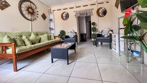 Un salon comprenant un canapé, deux fauteuils, une table basse et des œuvres d’art décoratives accrochées au mur.