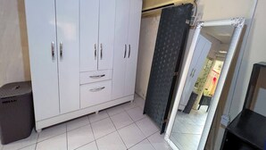 Une pièce avec une armoire blanche, une porte noire et un sol carrelé.