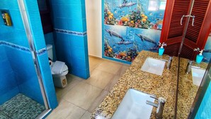 Ein Badezimmer mit blauen Fliesenwänden, einer Duschkabine und einem Waschbecken mit Marmorplatte.