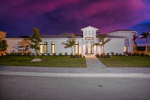 A modern house with a well-maintained lawn, a driveway, and a clear sky.