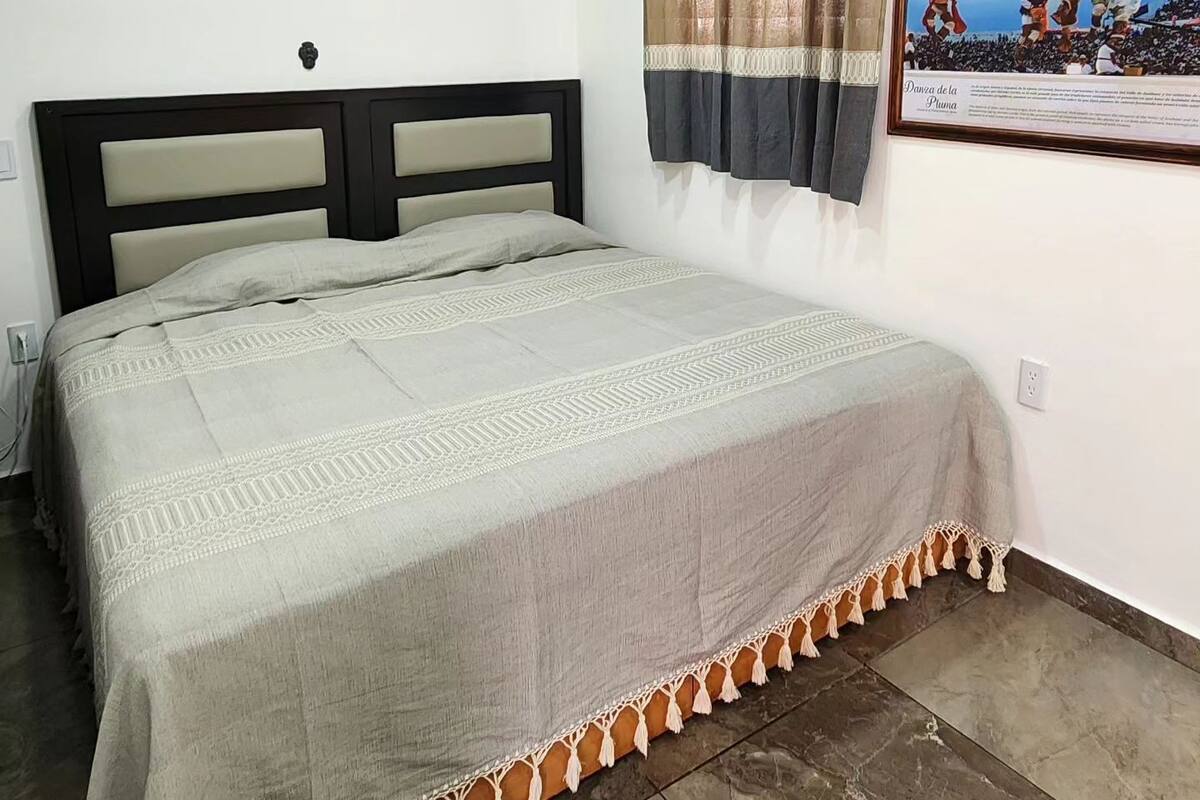A bedroom with a bed, a framed picture of a dancer, and a curtain.