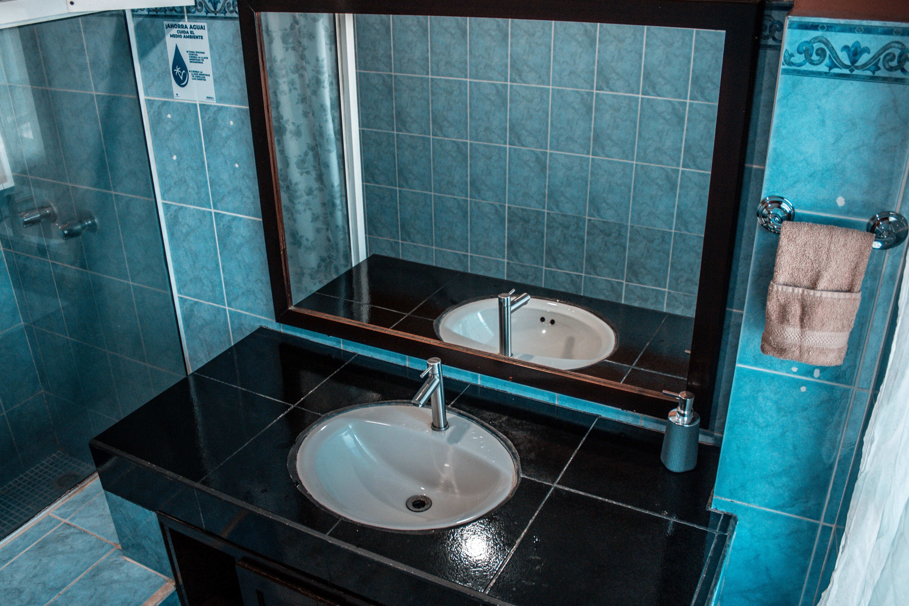 A bathroom with a black sink, a mirror, and a towel rack.