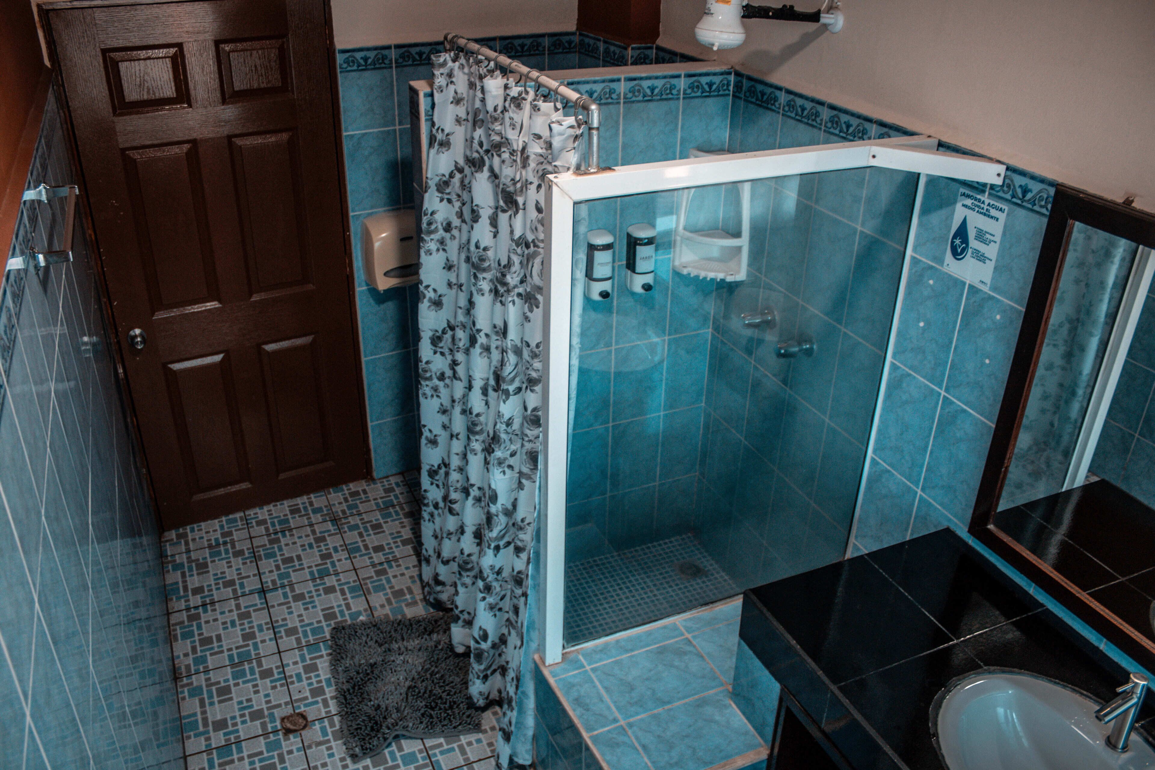 Een badkamer met een douche, een wastafel en een deur.