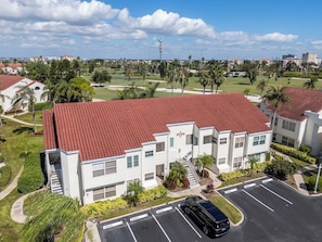 A multi-story residential building with a red-tiled roof, a parking lot, and a golf course in the background. - Isla Del Sol 1st Floor 2BD/2BA. Close to Beaches (St. Petersburg)