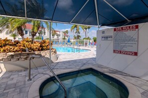 Ein Poolbereich mit Whirlpool, Liegestühlen und einem Schild mit Spa-Regeln.