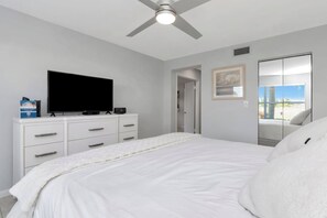 A bedroom with a bed, a television on a dresser, a ceiling fan, and a door leading to a balcony. - Isla Del Sol 1st Floor 2BD/2BA. Close to Beaches (St. Petersburg)