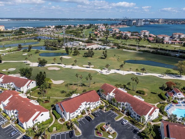 Un campo de golf con piscina, rodeado de edificios residenciales con tejados rojos.