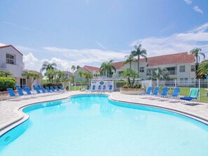 Una piscina con sillas de descanso y una cerca blanca.