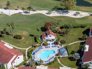 Ein Luftbild eines Resorts mit Swimmingpool, Liegestühlen und Palmen.