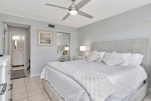 Un dormitorio con cama, ventilador de techo, mesita de noche y cómoda.