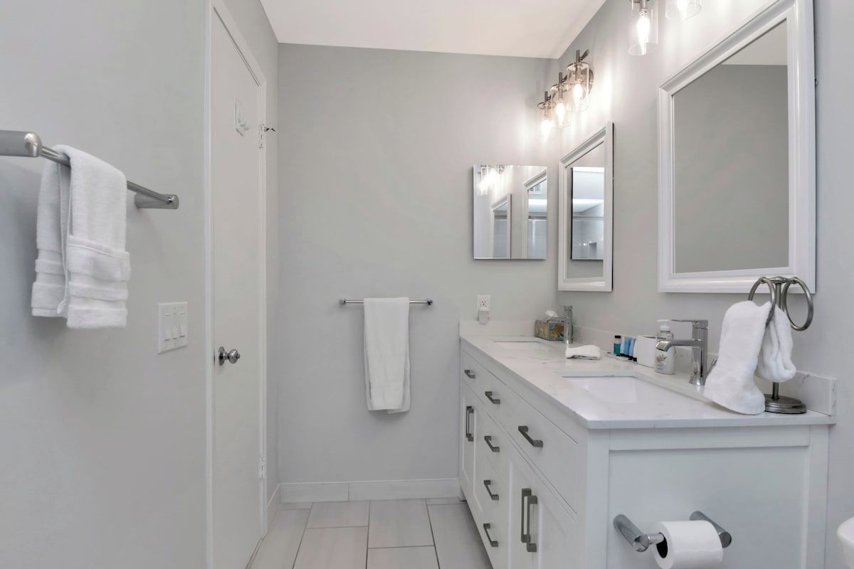 A modern bathroom with a white vanity, a large mirror, and a towel rack.