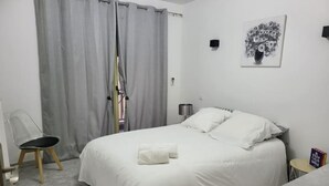 Une chambre à coucher avec un lit, une chaise, une lampe et un tableau au mur.
