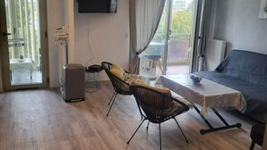 Un salon moderne comprenant un canapé, deux fauteuils, une table basse, un téléviseur à écran plat et une porte-fenêtre coulissante donnant sur un balcon.