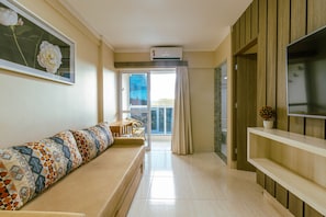Uma sala de estar moderna com sofá, televisão e varanda com vista.