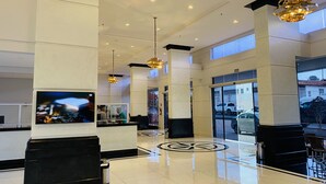 A spacious lobby with a high ceiling, modern lighting fixtures, a large TV screen, and a clear view of the outside through the glass doors. - Piazza diRoma - Vacia Temporada (Caldas Novas)