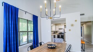 Un comedor con mesa de madera, cortinas azules y una lámpara de araña.