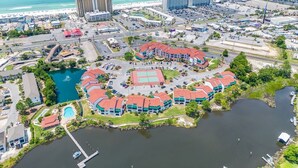 Luchtbeeld van een resort met meerdere gebouwen, een centraal gelegen zwembad en een jachthaven.