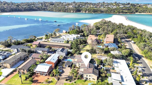 An aerial view of a coastal residential area with houses, a beach, and boats. - Calendo Apartmnts - Unit 1: Ground Floor (Merimbula)
