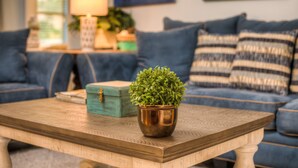 Ein Wohnzimmer mit Couch in Blau, einem Holztisch und einem kleinen Topfpflanzen.
