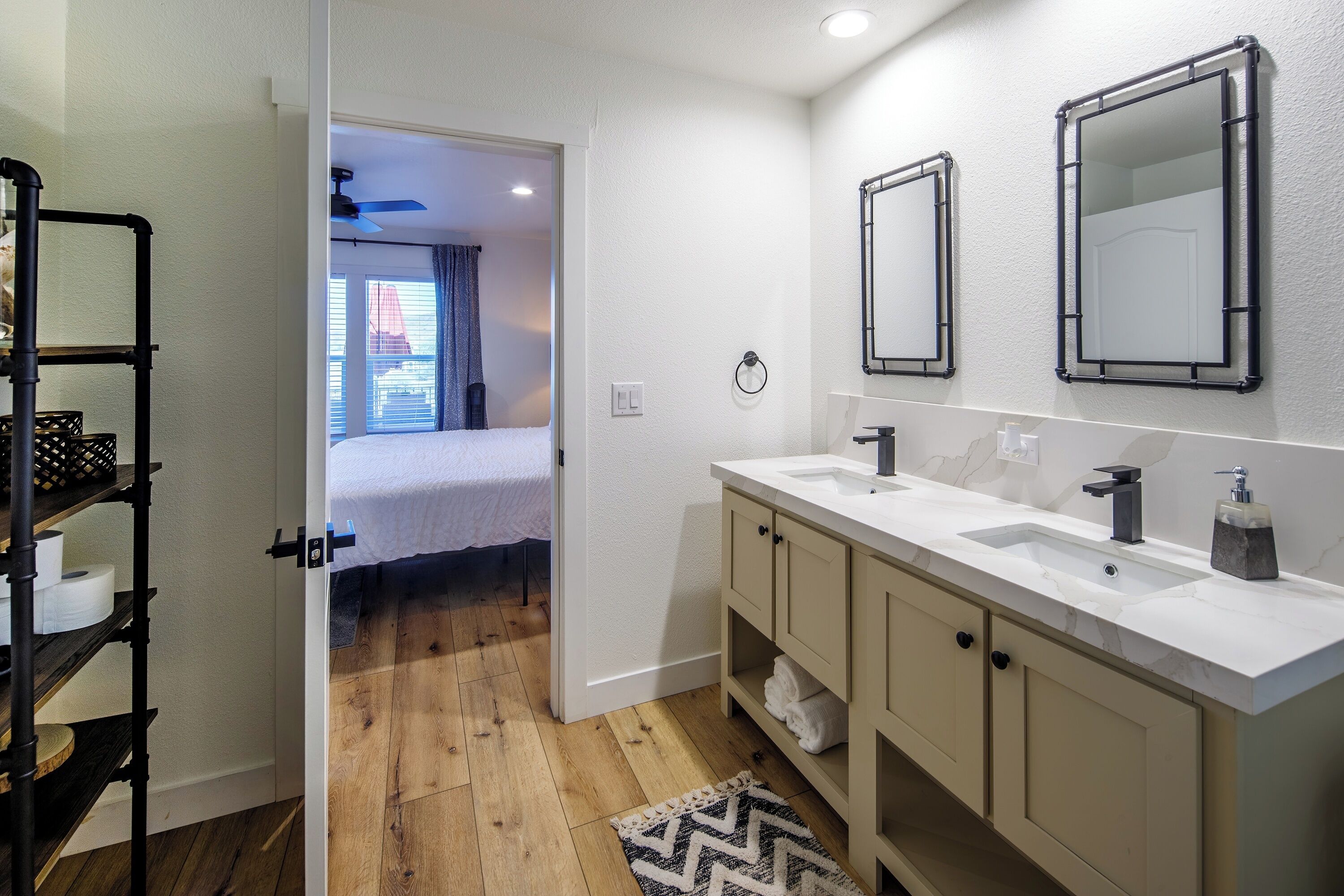 Un baño moderno con dos lavamanos, un espejo y suelo de madera.
