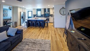Une cuisine moderne dotée d’un îlot central, de tabourets de bar et d’un grand téléviseur à écran plat.
