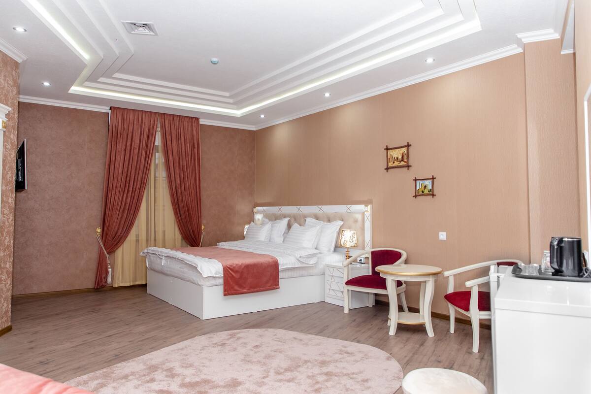 Habitación de hotel con una cama grande, un escritorio con una silla, una mesita redonda y una cafetera.