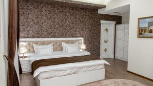 Un dormitorio con una cama grande, una mesita de noche, una lámpara y una puerta.