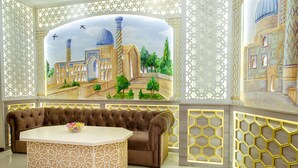 Una habitación con un gran mural de una mezquita, un sofá marrón y una mesa blanca con un diseño decorativo.