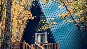 Eine Hütte mit steilem Dach, einer Holztreppe und einer umzäunten Terrasse.