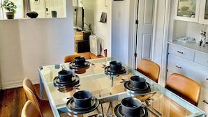 Un espace repas avec une table à plateau en verre, des assiettes noires et des chaises en cuir marron.