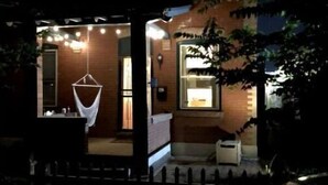Une maison moderne avec une entrée dotée d’une porte en verre, un luminaire suspendu et un petit espace porche.