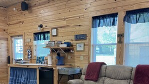 A cozy cabin interior with a wooden interior, a kitchenette, a sofa, and a patterned rug.
