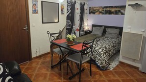 Una camera da letto con un letto, una scrivania con una sedia, una TV fissata al muro e una porta con un numero sopra.