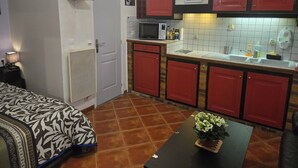 Una cucina compatta con mobili rossi, un forno a microonde e uno schienale piastrellato.