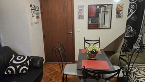 Zona pranzo con tavolo, sedie, una pianta in vaso e un divano a righe bianche e nere.