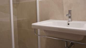 Une salle de bain avec une douche, un lavabo et un miroir.