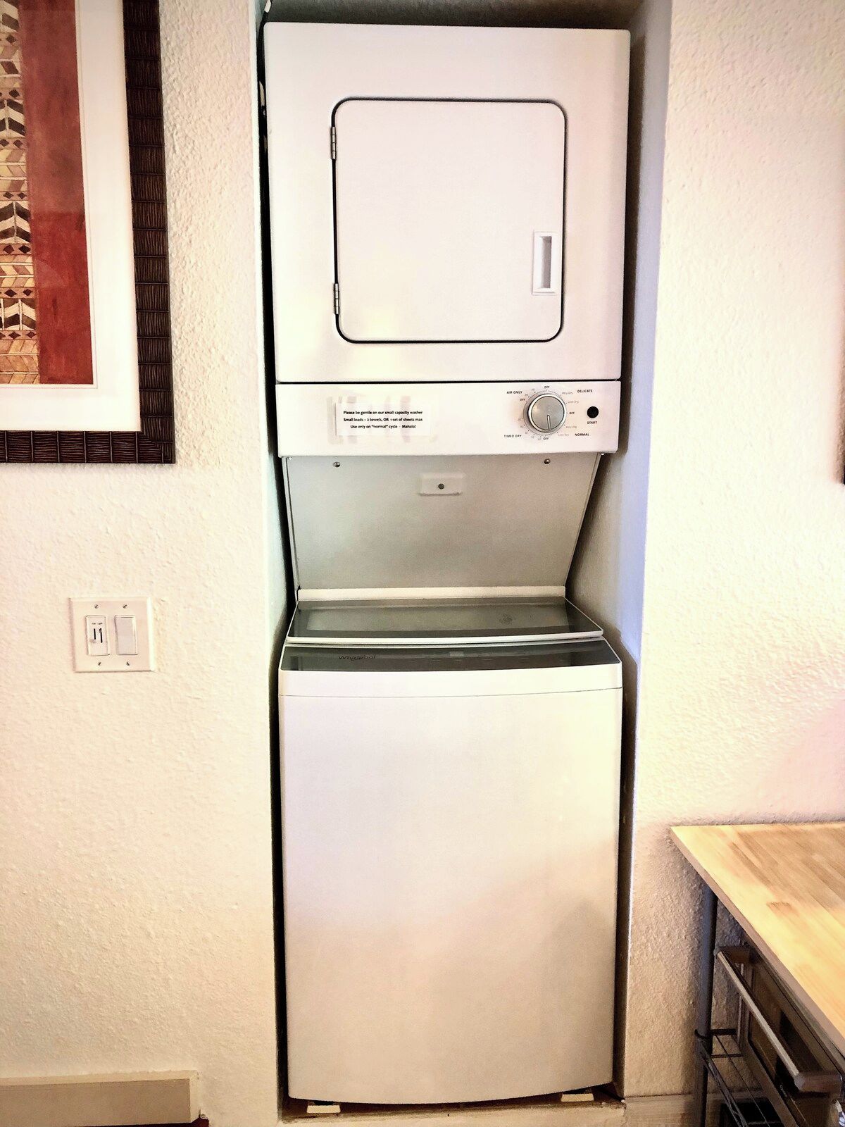 A compact, wall-mounted washer and dryer unit with a control panel and a small window.