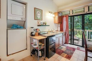 Eine kompakte Küche mit Kühlschrank, Mikrowelle und Spüle. Es gibt einen kleinen Essbereich mit Tisch und Stühlen.