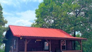 A rustic log cabin with a red roof, a porch, and a sign reading "NEWLYWED". - Romantic Cabin with Jacuzzi Tub. Ride-in Access to Wolf Pen Gap ATV trails  (Mena)