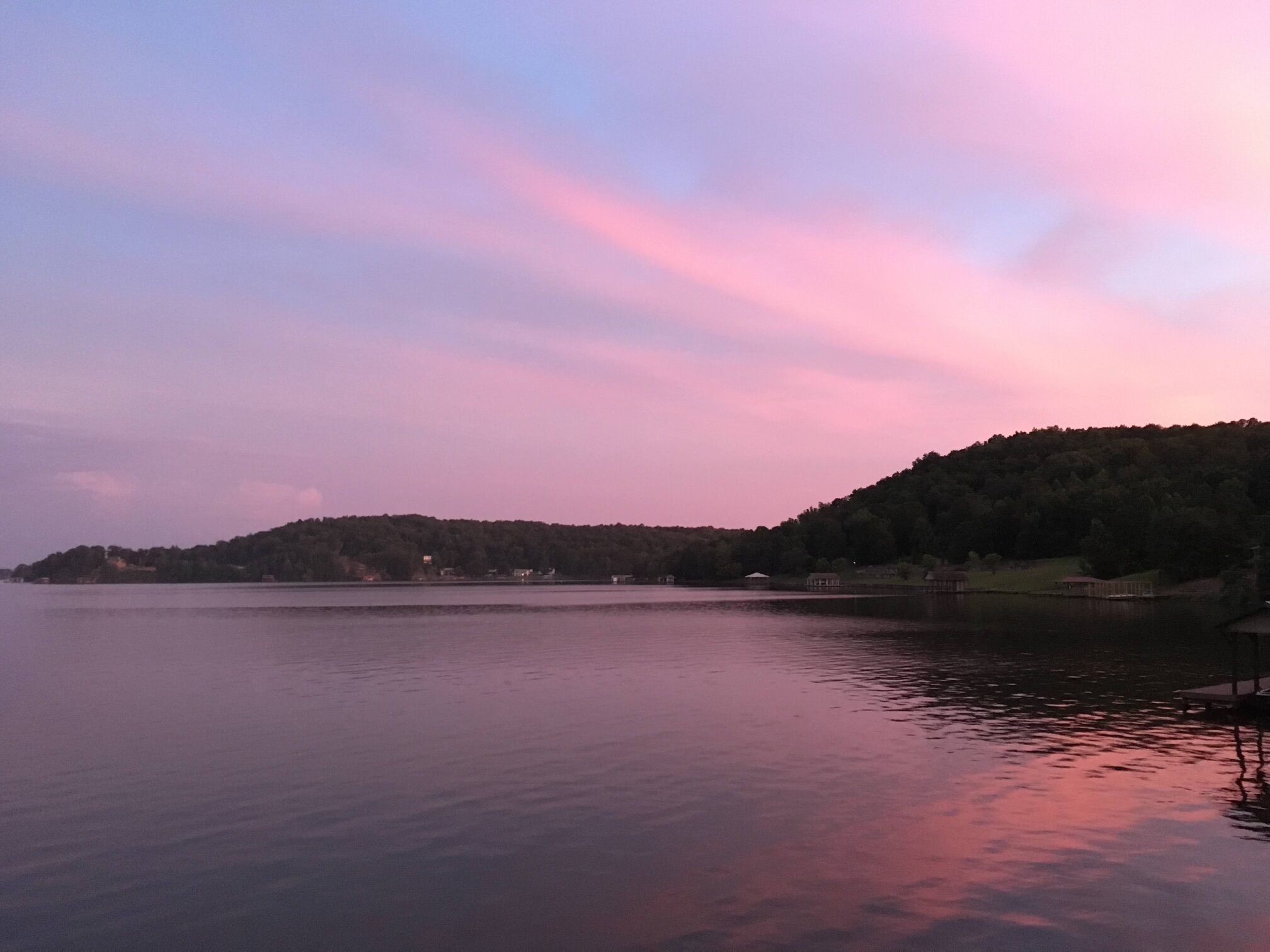 A calm lake with a forested hill in the background.