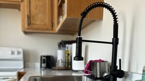 A kitchen sink with a modern faucet, a marble countertop, and wooden cabinets in the background. - Brickhaven Loft on Historic Main Street - walk to Spring River, State Park, more (Mammoth Spring)