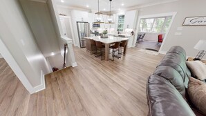 A modern kitchen with white cabinets, stainless steel appliances, and a central island with chairs. - Newer property at Kerr Lake with dock! Family-sized with game room and lg porch! (Manson)