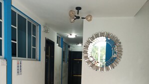 Ein Flur mit einem dekorativen Spiegel, einem Deckenventilator und einer Treppe mit Holzwandungen.